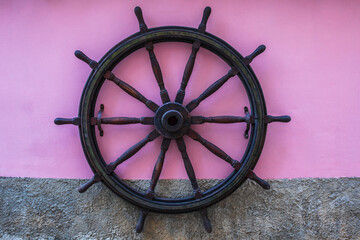 Nautical Vintage Ship's Wooden Steering Wheel Against Purple Wall