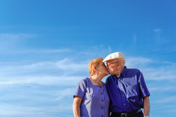 Senior couple kissing with sky for copy space. Love and affection in old age.