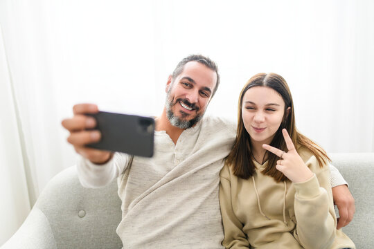father with teen child daughter having fun using cellphone at home