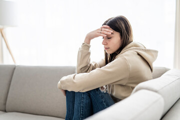 teen sitting on couch at home Frustrated confused female feels unhappy problem in personal life