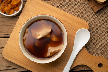 Boiled Soft tofu pudding (soy bean curd) in ginger juice soup in a bowl.Top view