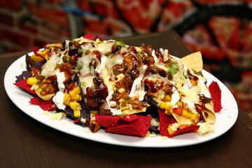 Nachos with different colored shells; with meat, cheese, barbeque sauce, garlic sauce, jalapenos,...