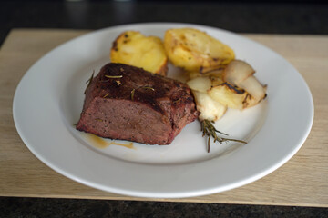 ready to eat -venison from a red deer calf, potaotes and onions grilled of a charcoal grill