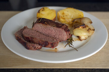 ready to eat -venison from a red deer calf, potaotes and onions grilled of a charcoal grill