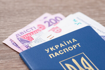Ukrainian hryvnia banknotes in ukrainian passport, close up on grey table. Salary, earnings, savings and financial deals in Ukraine concept