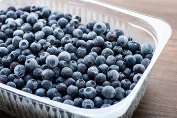 Tasty juicy ripe blueberries in plastic bowl. Frozen food for winter, vitamins, healthy nutrition
