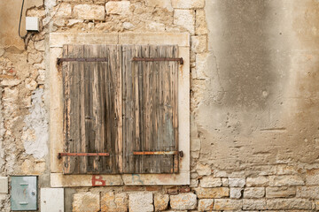 Fototapeta na wymiar Old wooden shutters, window shutters, closed shutters and stone wall of an old house.