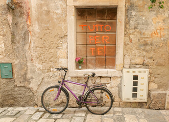 Fototapeta na wymiar An old bicycle, an old stone street, a window closed with wooden shutters with the inscription Everything for You. Street in Croatia.