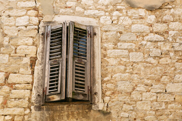 Closed rustic brown wooden window shutters on the background of an old white stone wall. Copy space