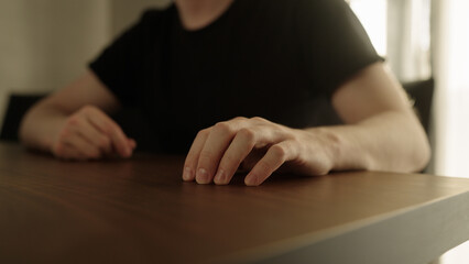 Man finger tap on walnut wood table indoor