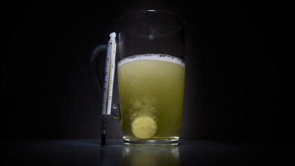 Top view of water soluble pills next to a glass thermometer showing fever symptoms