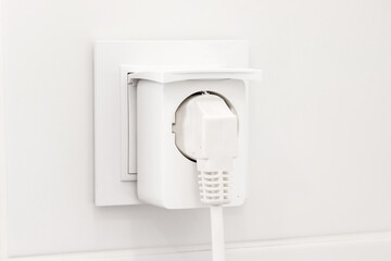 White european electrical outlet with smart plug inserted into it on modern bright bathroom with...