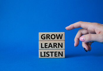 Grow Learn Listen symbol. Concept words Grow Learn Listen on wooden blocks. Businessman hand. Beautiful blue background. Business and Grow Learn Listen concept. Copy space