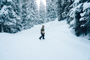 A boy playing in snow. forest. Fir trees covered with snow on frosty morning. Winter holiday concept. Special filter, selective focus.