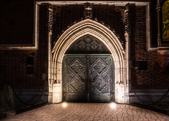 stara zdobiona brama spiżowa kościoła w nocnym oświetleniu