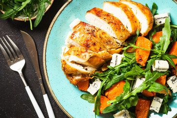 Healthy salad with baked chicken breast, pumpkin, blue cheese and arugula. Healthy diet food.