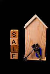 wooden house mockup with house keys, wooden cubes with words rent sale , buy and loan. on black background