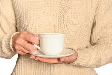A woman in a white jumper holds a white cup and saucer. Autumn concept.