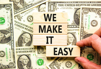 We make it easy symbol. Concept words We make it easy on wooden cubes. Beautiful background from dollar bills. Businessman hand. Business motivational we make it easy concept. Copy space.