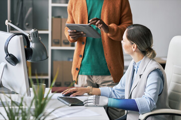Female entreprneur with bionic arm talking to colleague