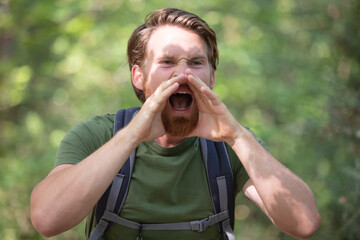 young man standing alone in woods and yelling
