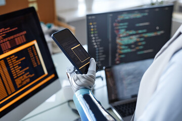 Closeup image of software developer with prosthetic arm testing code on smartphone