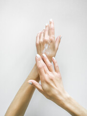 a woman applies a moisturizing lotion to her hands on a white table background. hand care concept
