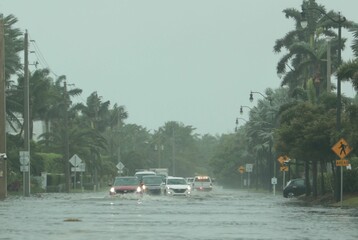 Obraz premium Flooded road with cars passing through during hurricane Nicole in Palm Beach, Florida. November 2022
