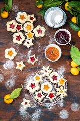 Traditional Linzer Christmas cookies filled with lingonberry jam and orange jam on wooden background