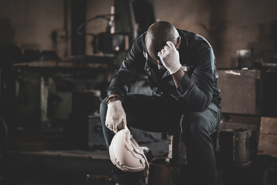 Unhappy and tired male industrial worker with headache working in hardworking position