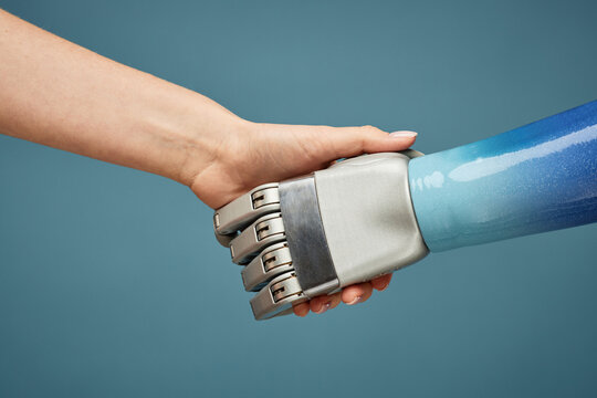 Closeup image of person shaking hand of robot, artificial intelligence concept