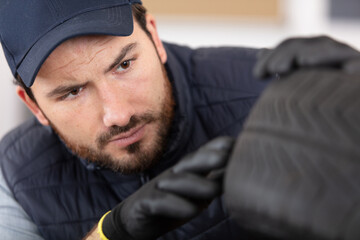Fototapeta premium young car mechanic inspecting tyre