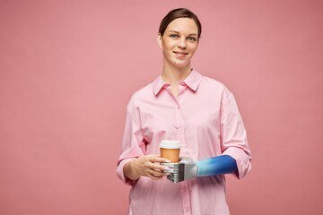 Positive woman with prosthetic arm holding disposable cup of coffee