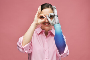 Portrait of happy excited young woman making binoculars with bionic hand