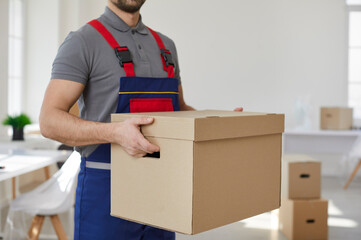 Close up of male carrier or mover in uniform hold cardboard box help client with relocation or...