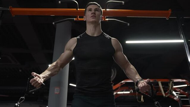 Athletic man doing expander workout in fitness gym. Athlete exercising with fitness expander in gym