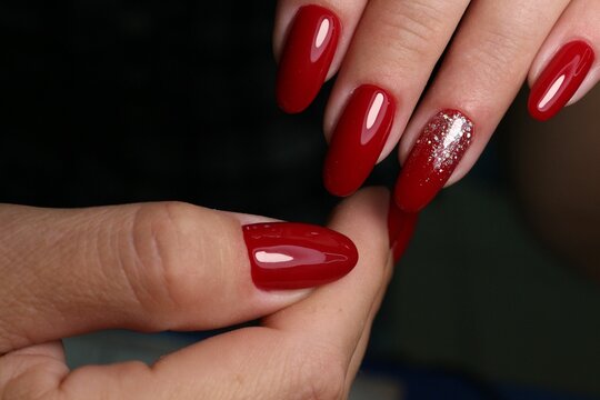 Closeup Shot Of Red Sexy Manicure Of Female's Long Nails On A Wooden Background