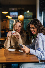 Two women looking at phone in a cafe