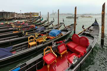 Fototapeta na wymiar Traditional gondolas at the pier with the island of San Maggiore in the background.