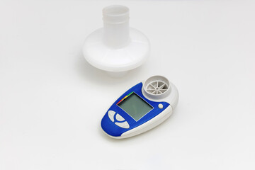 Asthma medications inhalers and peak flow meter on a white background.