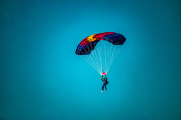 Skydiver on a colorful parachute flies in the clear sky