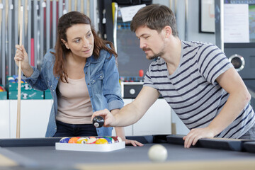 man guiding girlfriend at billiard table