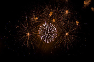 White, beige and yellow fireworks burst into various shapes in the sky