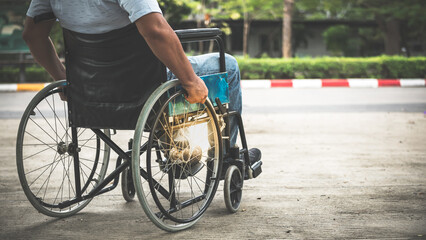 Behind an Asian elderly man traveling in a wheelchair by himself, to people and health care concept.