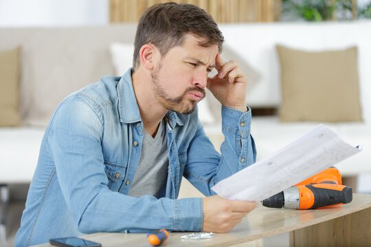frustrated man sighing while reading complicated assembly instructions