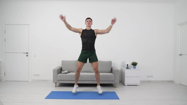 Sport man athlete doing jumping jacks with claps. Fitness man doing cardio fitness workout at home