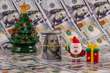 Symbolic figurine of Santa Claus and banknotes of 100 US dollars