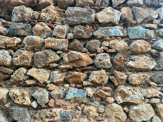 Background, texture, stone wall of round stones cobblestones bricks natural surface natural sharp convex rough stone cobblestone with cracks