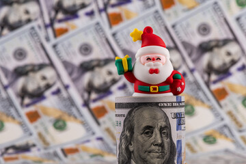 Symbolic figurine of Santa Claus and banknotes of 100 US dollars