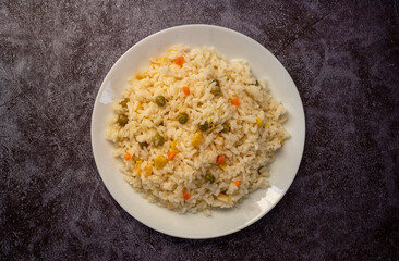 Vegan rice with vegetables, shot from above on a black background